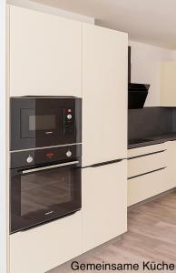 a kitchen with a stove and a microwave at ESER - Haus am Vogesenblick in Bad Bellingen