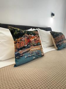 two pillows on a bed with a painting of a harbor at Maison Miry in Rapallo