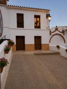 a white building with brown doors and flowers at Apartamento Luna in Cártama