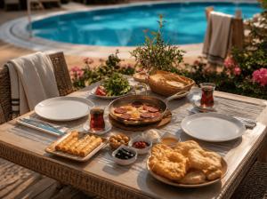 a table with food on it next to a pool at Bella Rose Apart Hotel, Alanya in Alanya