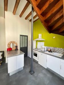 a kitchen with white cabinets and a green wall at La Canetterie in Dole