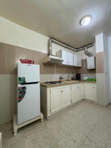 a kitchen with white cabinets and a white refrigerator at Dar KAMOUN - 2BR Apts with 5G WiFi & Parking, Houmt Souk & Corniche in Houmt Souk