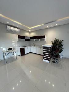 a large kitchen with white cabinets and a table at شاليهات دبليو العمارية W Chalet in Al ‘Ammārīyah