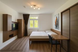 a bedroom with a bed and a desk and a window at ESER Hotel Pension in Beuggen