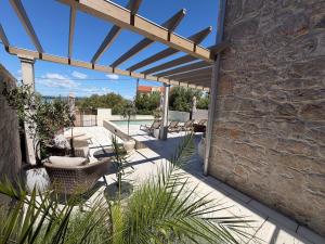 a patio with a stone wall and a wooden pergola at Heritage Villa Francheza-Elegant Stone villa near the Beach, Pašman Island , Ugrinić in Ugrinići