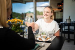 a woman sitting at a table with a glass of wine at Nuhr Medical - Hotel & Restaurant - Ab 3 Nächten im Zeitraum vom 06 Juli bis 30 August genießen Sie pro Person eine kostenlose Massage-Unser Naturteich steht Ihnen täglich von 10 Uhr bis 18 Uhr zur Verfügung inklusive Getränke in Senftenberg +59 photos