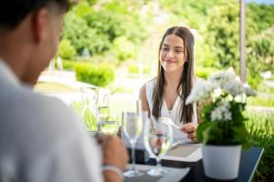 a woman sitting at a table talking to a man at Nuhr Medical - Hotel & Restaurant - Ab 3 Nächten im Zeitraum vom 06 Juli bis 30 August genießen Sie pro Person eine kostenlose Massage-Unser Naturteich steht Ihnen täglich von 10 Uhr bis 18 Uhr zur Verfügung inklusive Getränke in Senftenberg