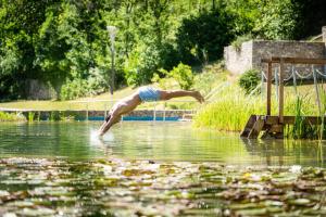 a man diving into a body of water at Nuhr Medical - Hotel & Restaurant - Ab 3 Nächten im Zeitraum vom 06 Juli bis 30 August genießen Sie pro Person eine kostenlose Massage-Unser Naturteich steht Ihnen täglich von 10 Uhr bis 18 Uhr zur Verfügung inklusive Getränke in Senftenberg