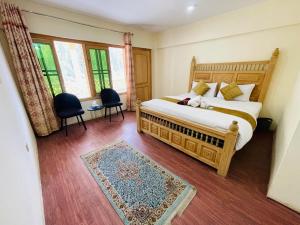 a bedroom with a bed and two chairs and windows at IBEX COTTAGE SHARDa in Shardi +13 photos