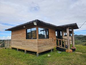 a wooden cabin with a black roof on a grass field at cabaña sol in Santa Elena