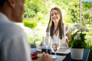a woman sitting at a table talking to a man at Nuhr Medical - Hotel & Restaurant - Ab 3 Nächten im Zeitraum vom 06 Juli bis 30 August genießen Sie pro Person eine kostenlose Massage-Unser Naturteich steht Ihnen täglich von 10 Uhr bis 18 Uhr zur Verfügung inklusive Getränke in Senftenberg