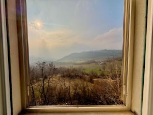 a window with a view of a field and mountains at B&B Il COTOGNO - Cucina e Parcheggio Privato in Serramazzoni
