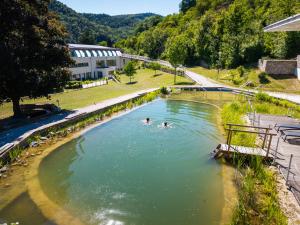 two people swimming in a pool of water at Nuhr Medical - Hotel & Restaurant - Ab 3 Nächten im Zeitraum vom 06 Juli bis 30 August genießen Sie pro Person eine kostenlose Massage-Unser Naturteich steht Ihnen täglich von 10 Uhr bis 18 Uhr zur Verfügung inklusive Getränke in Senftenberg