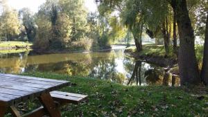 - une table de pique-nique à côté d'une rivière arborée et d'un rebord de rivière dans l'établissement La Maison dans la Prairie, à Bernot