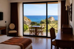 a hotel room with a bed and a view of the ocean at Vila Foz Club - Algarve in Alvor +35 photos