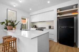 a kitchen with white cabinets and a black refrigerator at 3BR Light-filled Retreat Mt Duneed in Mount Duneed