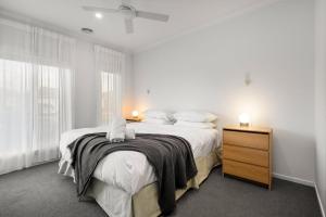 a white bedroom with a large bed and a dresser at 3BR Light-filled Retreat Mt Duneed in Mount Duneed