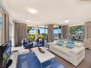 a living room with a white couch and a tv at Excellsior Apartments in Mooloolaba