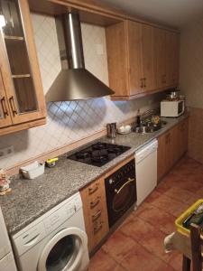 a kitchen with a stove and a washing machine at La Ribera del Río in Trefacio