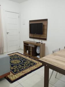 a living room with a flat screen tv and a table at Recanto Tarobá in Ponta Grossa