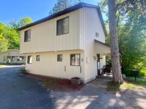a white house with a tree in front of it at Betsie Riverside Resort in Benzonia