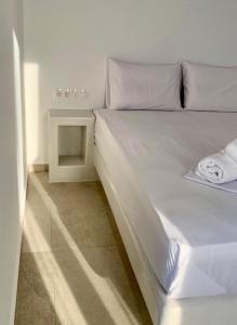 a white bed in a room with a side table at AiΘeria Suites Ios in Ios Chora