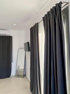 a room with black curtains and a mirror at AiΘeria Suites Ios in Ios Chora +9 photos