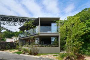 a glass house with a bridge in the background at Seaside Villa SEEN Shallow Sea in Onomichi