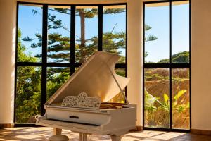 a white piano in front of large windows at Vila Foz Club - Algarve in Alvor