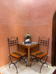 a table with two chairs and a table with flowers at Riad Afriquia Garden in Marrakesh