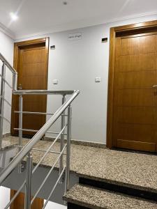 a hallway with two wooden doors and stairs at APARTAMENTOS ALBATROS in Asilah