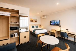 a hotel room with a bed and a desk at Glenelg Motel in Adelaide