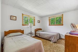 a bedroom with two beds and two windows at Cabin #5 3BR 2BA Timberlane Resort in Park Rapids
