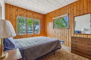 a bedroom with a bed and a dresser and two windows at Cabin #5 3BR 2BA Timberlane Resort in Park Rapids