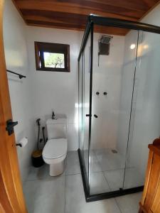 a bathroom with a toilet and a glass shower at Chalé Terra Nova in Itamonte +22 photos