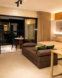 a bedroom with a bed and a couch and a table at Studio na Av Esmeraldas com garagem in Marília