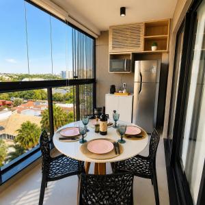 a kitchen with a table and chairs and a large window at Studio na Av Esmeraldas com garagem in Marília