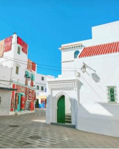 a white building with a green door in a street at APARTAMENTOS ALBATROS in Asilah