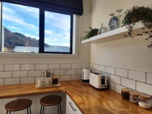 a kitchen with a counter with two stools and a window at Riverside retreat, Wanaka in Albert Town