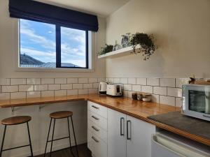 a kitchen with a counter with stools and a window at Riverside retreat, Wanaka in Albert Town