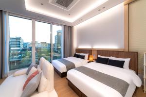 two beds in a hotel room with a large window at STAY On-A in Seoul