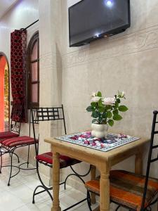 a table with chairs and a tv on a wall at Riad Afriquia Garden in Marrakesh