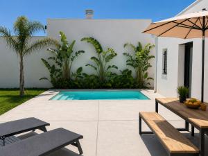a swimming pool with two benches and an umbrella at Oasis Blue Perpignan Canet in Perpignan