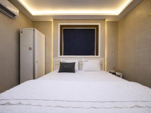 a bedroom with a large white bed with a window at 대구 동천 스위트 호텔 in Daegu