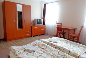 a bedroom with two beds and a table and a television at Penzión Reduta in Oravský Podzámok