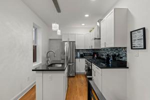 a kitchen with white cabinets and black counter tops at Modern 3BR Home Patio Near Center City Free Parkin in Philadelphia