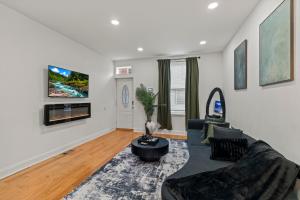 a living room with a couch and a tv on a wall at Modern 3BR Home Patio Near Center City Free Parkin in Philadelphia