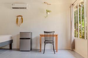a chair in a room with a refrigerator and a table at Rooms & Pool Macaws in Uvita