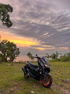 a motorcycle parked in a field with a sunset at RMBC beds and breakfast in Badian