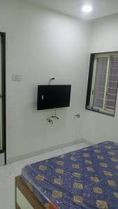 a bedroom with a bed and a flat screen tv on the wall at Munot residency in Manmād